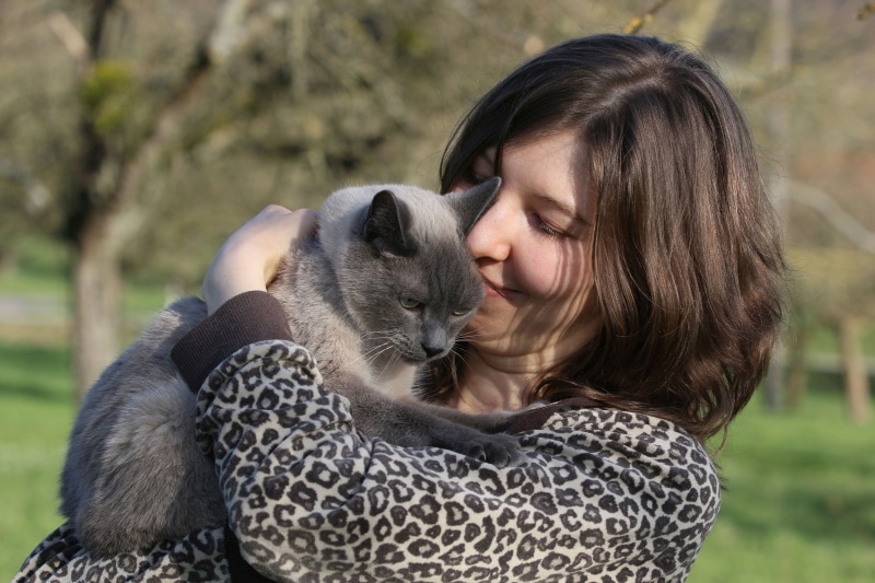 vrouw knuffel haar siamese kat