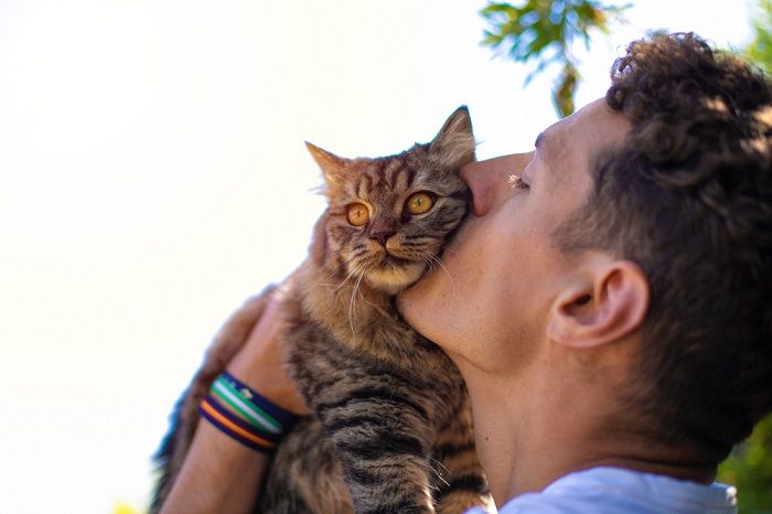 man in de tuin knuffelen en kussen van een kat