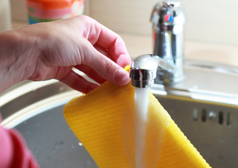 vrouwenhanden wassen de gele doek