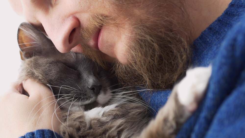 Bebaarde man knuffelt liefdevol zijn kat