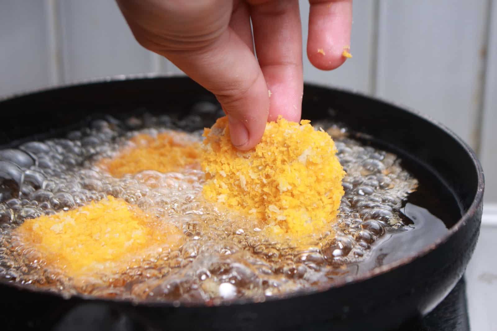 Close-up afbeelding van chef-kok die kipnuggets tempura in een hete oliepan doet